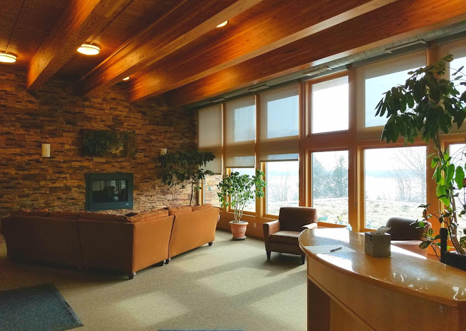 Reception area with seating and a desk next to large windows.