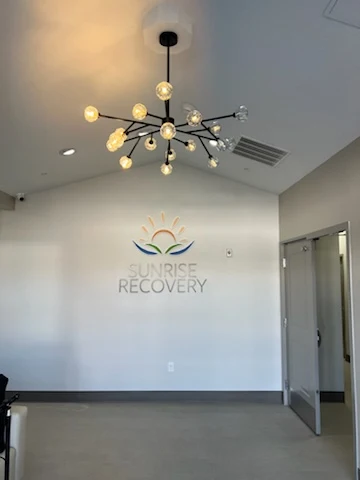 Wall with Sunrise Recovery logo and modern chandelier