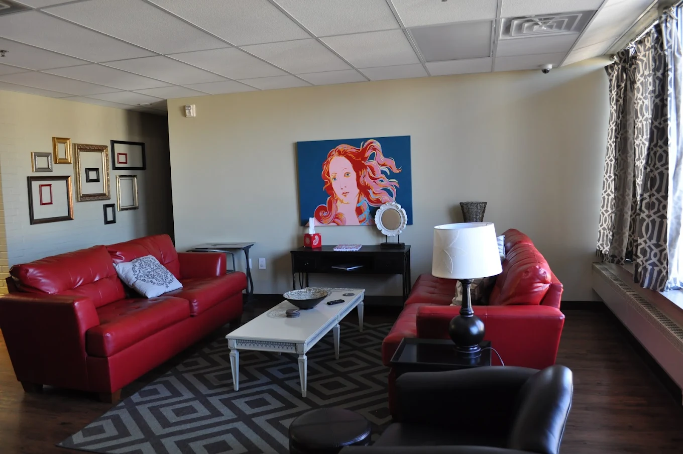 Living room with red sofas and colorful portrait on wall