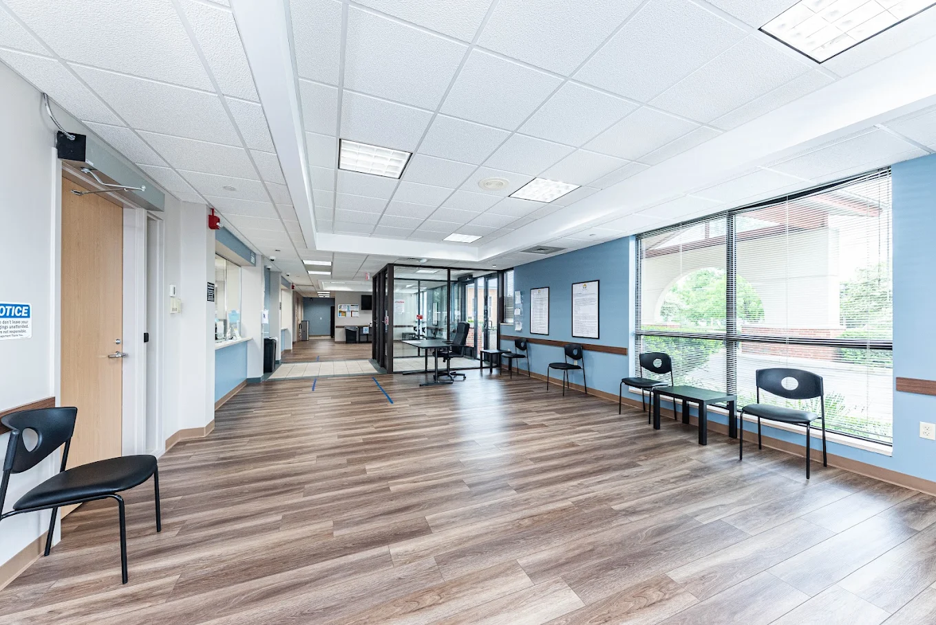 Spacious BrightView Health waiting area with black chairs, side tables, large windows, blue accent walls, reception area, and wood-look flooring