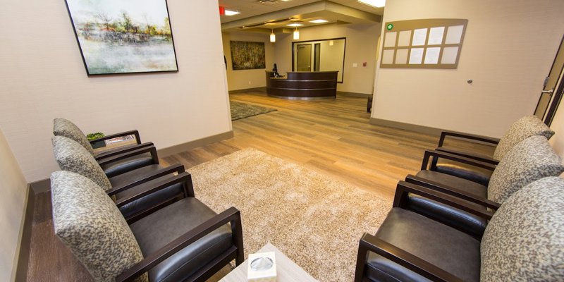 A modern waiting area with comfortable seating, soft lighting, and serene artwork. The open layout and clean design create a welcoming atmosphere.