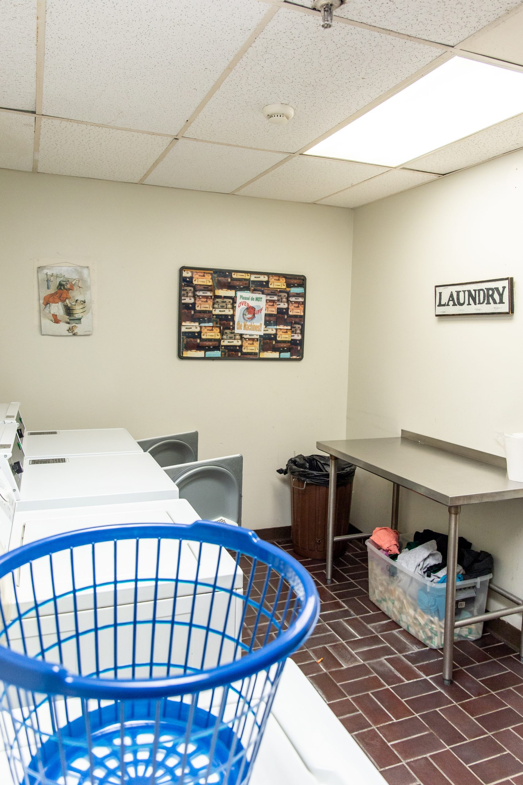 Laundry room with washers, dryers, folding table, and basket