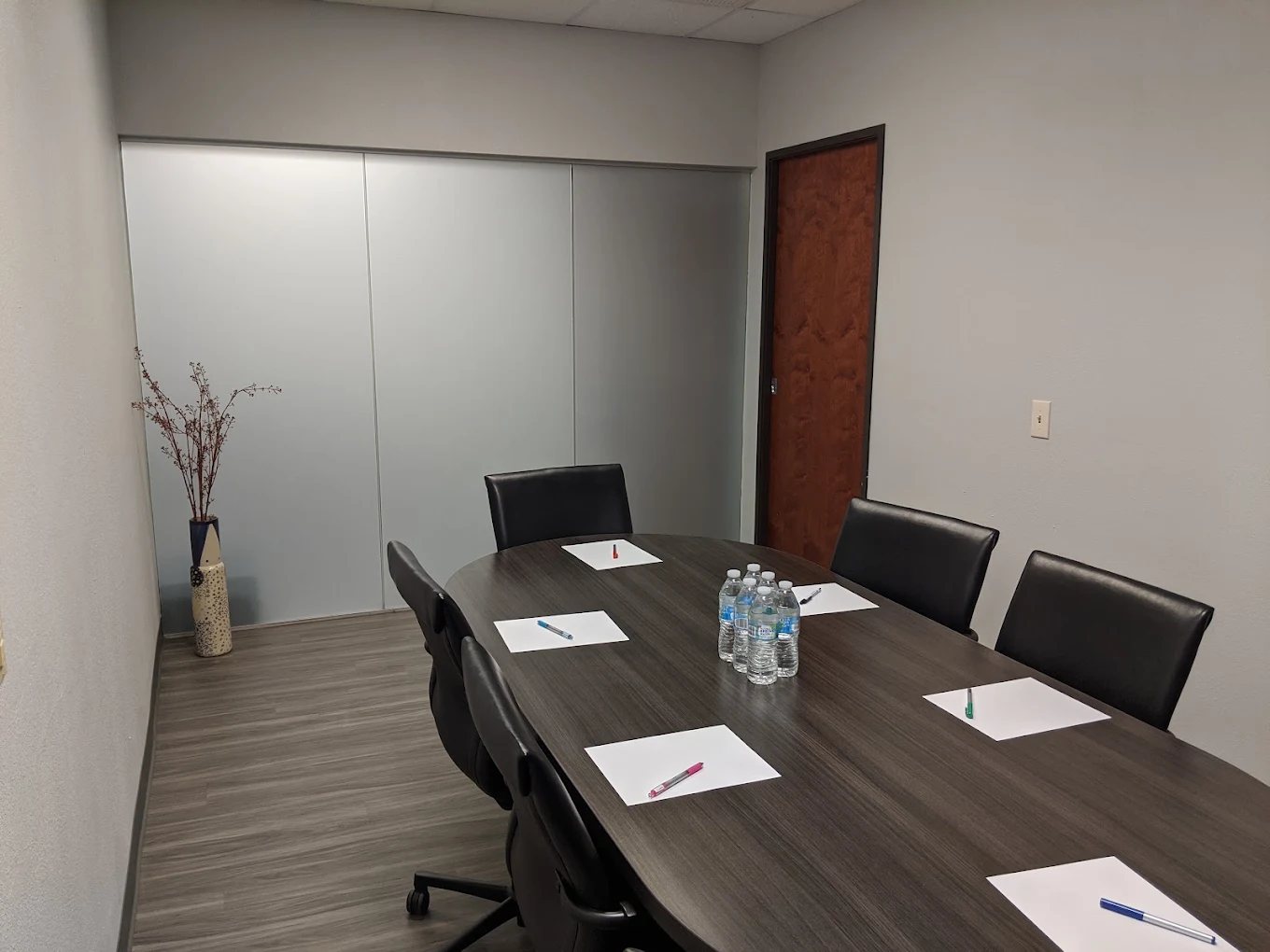 Conference table with chairs, writing pads, and bottled water