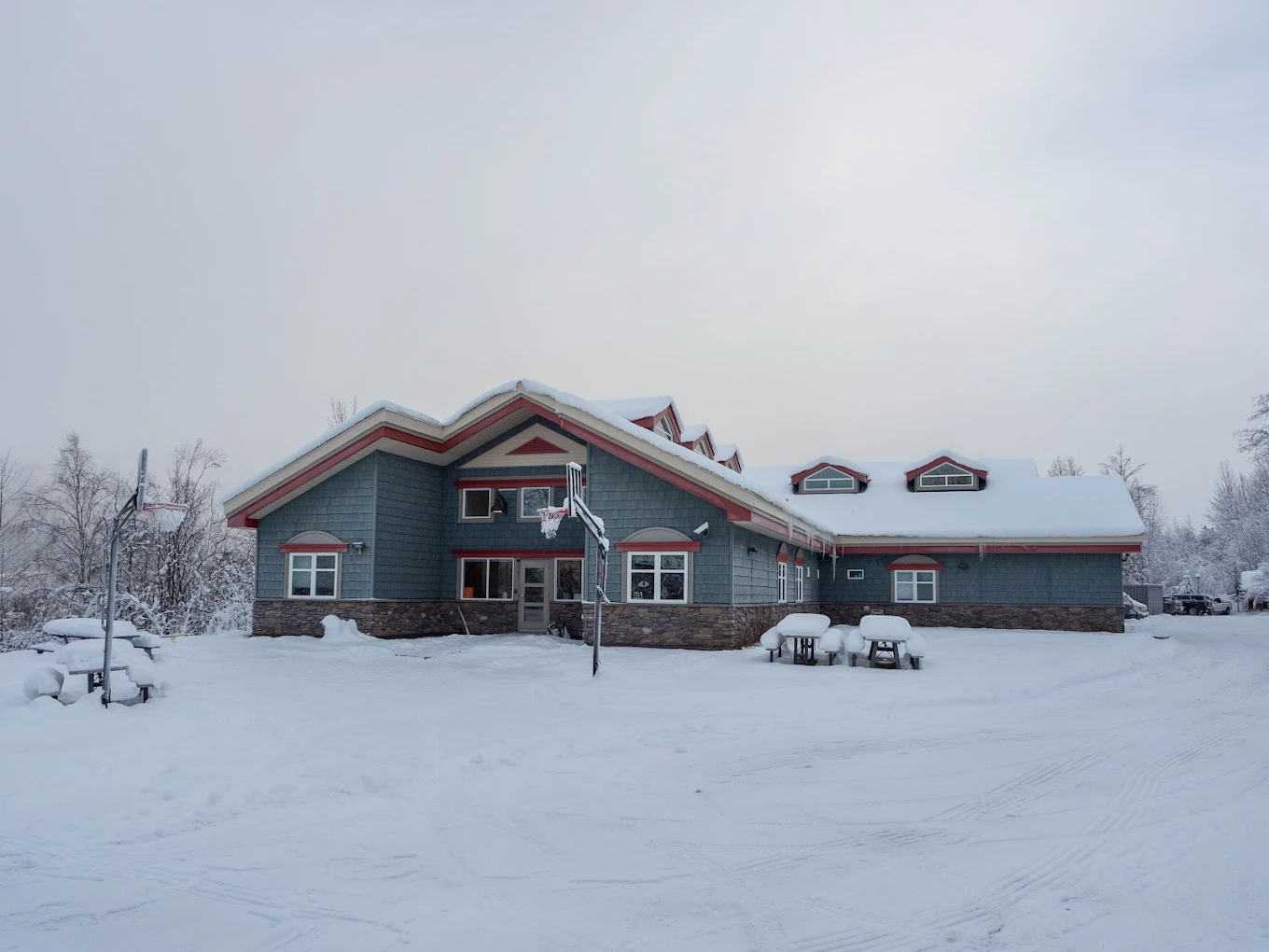 Facility exterior covered in snow with basketball hoop outside