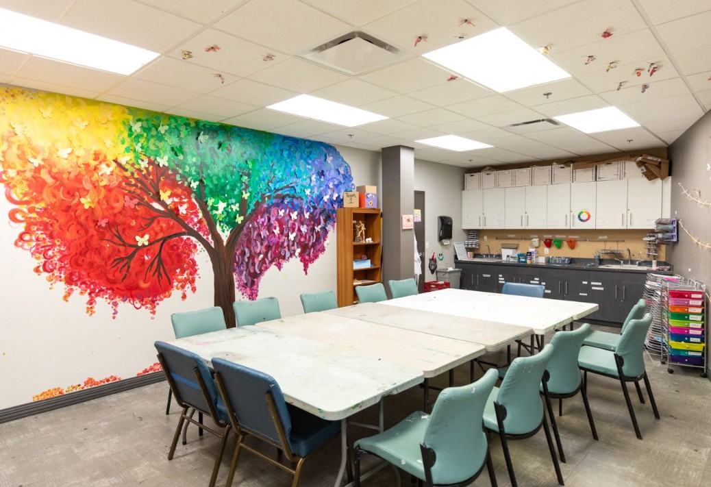Art room with tables, chairs, and colorful wall mural