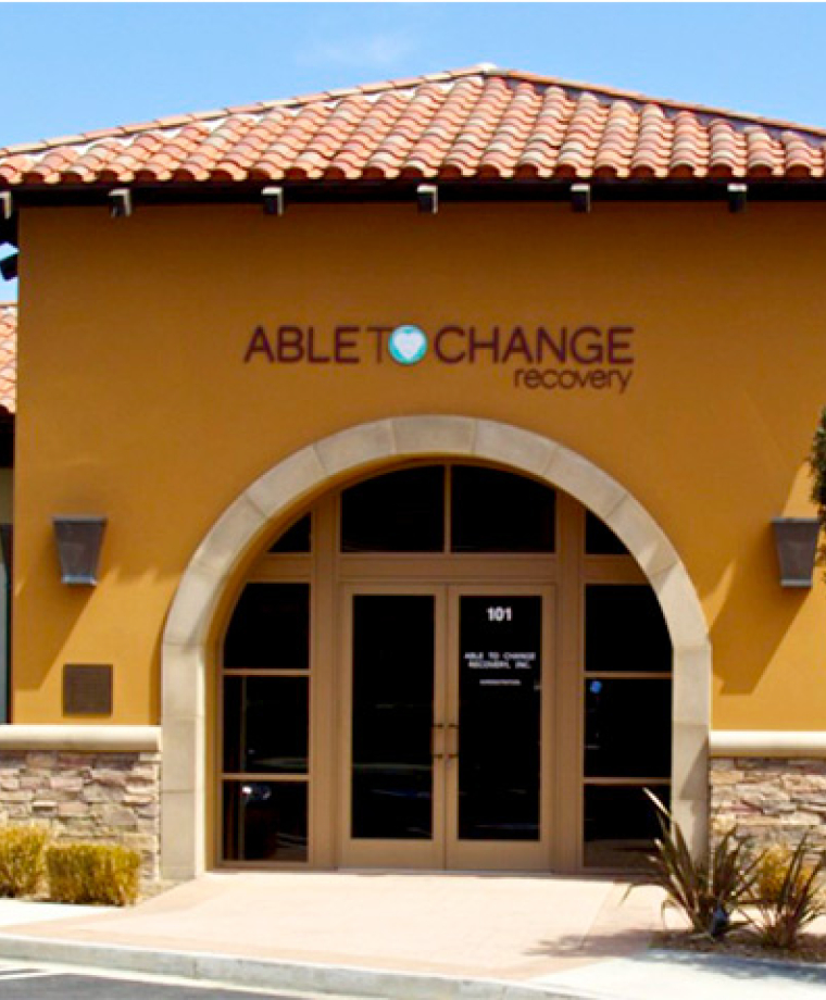 Tan building with arched entrance and tile roof at rehab center
