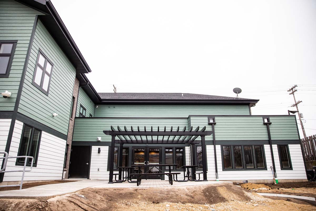 Patio with picnic tables under pergola behind facility