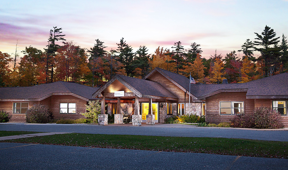 Wood building exterior surrounded by autumn trees at sunset