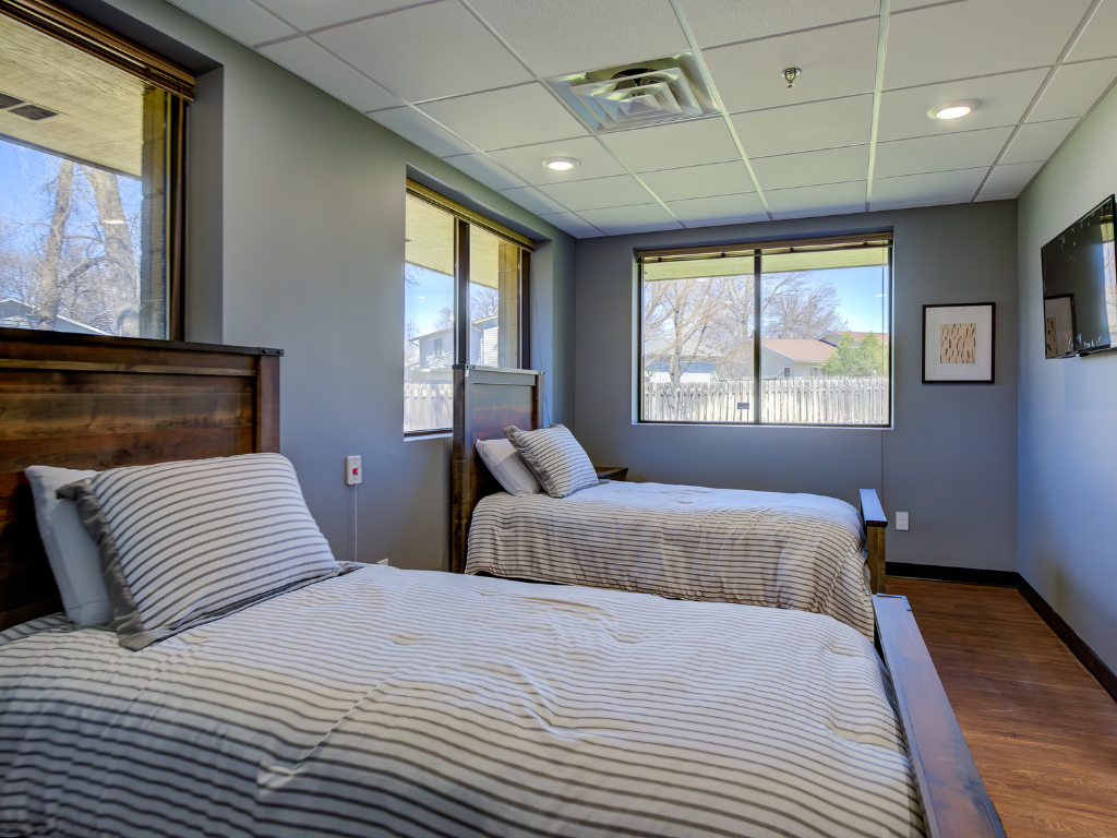 Two twin beds in a room with large windows and striped bedding