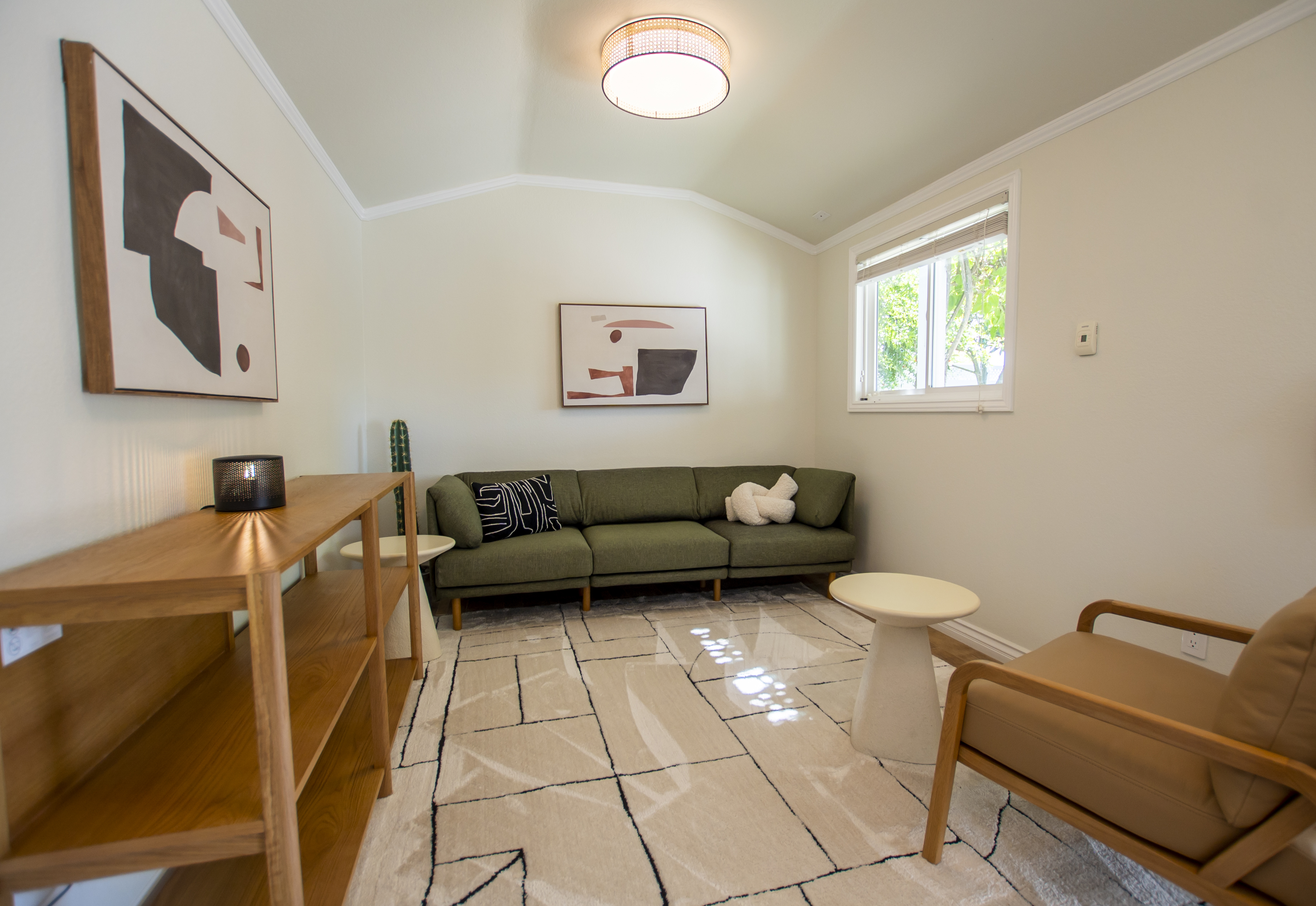 Small lounge with green couch and abstract wall art