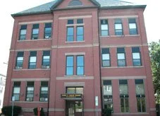 Brick rehab facility exterior with four stories and front entrance sign.