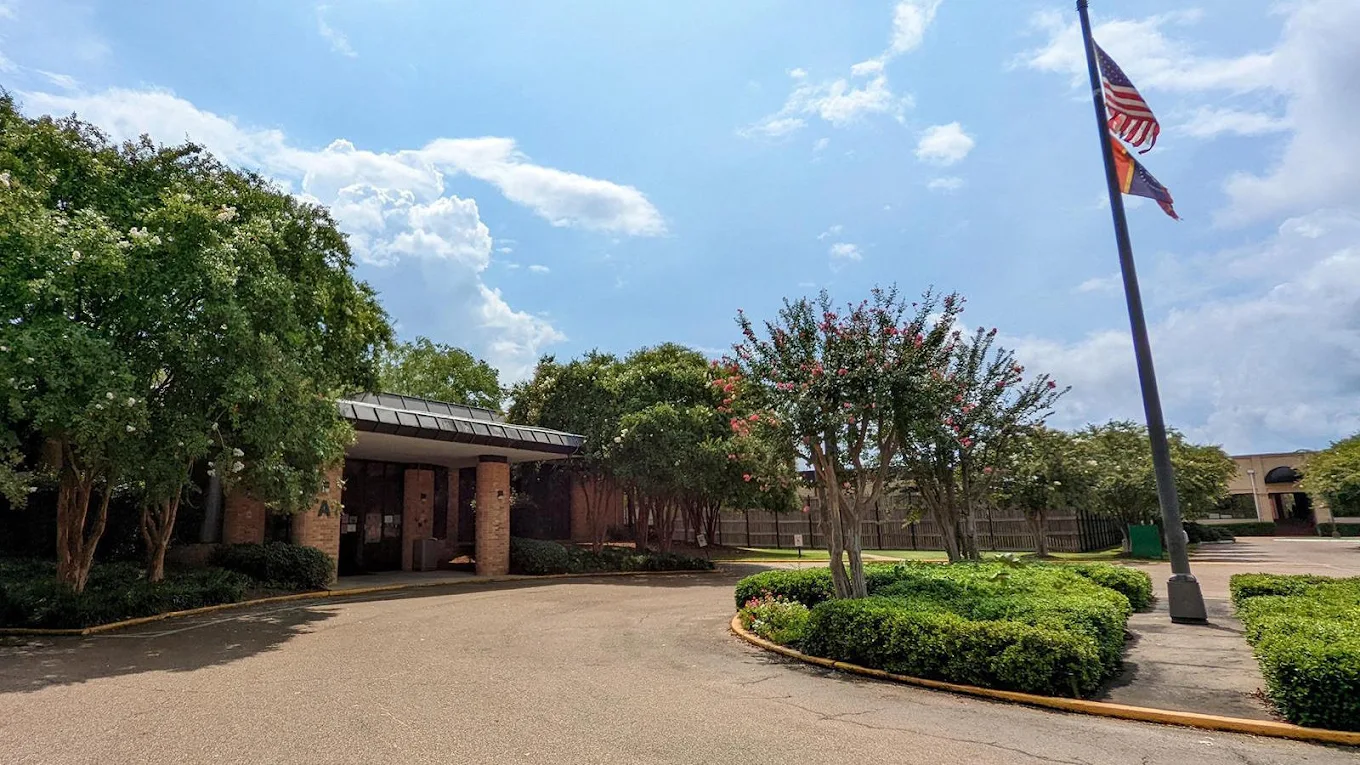 Main entrance with flags, trees, and landscaped grounds