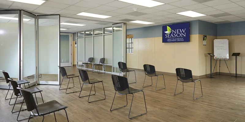 Bright and spacious group therapy room with modern chairs arranged for social distancing, featuring a warm, welcoming atmosphere for sessions.