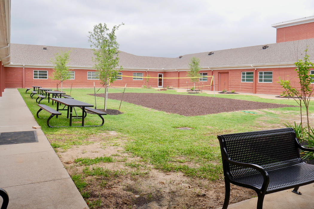 Outdoor courtyard with volleyball court and picnic tables