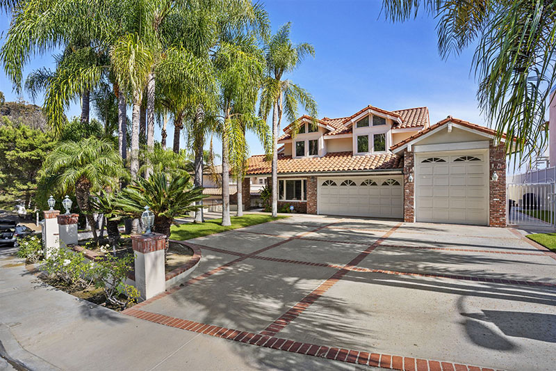 A large rehab facility with a driveway lined by tall palm trees.