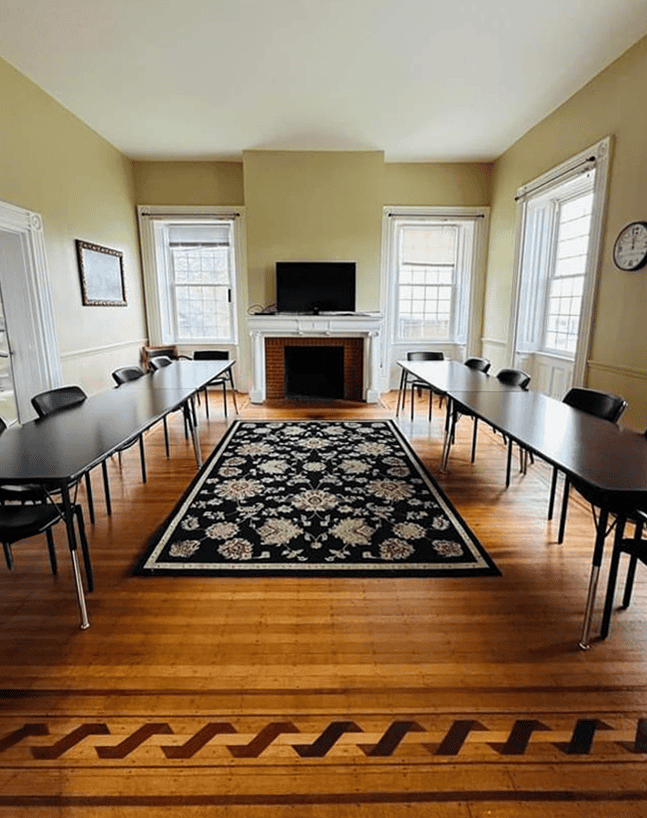 Group therapy room with tables, chairs, and TV