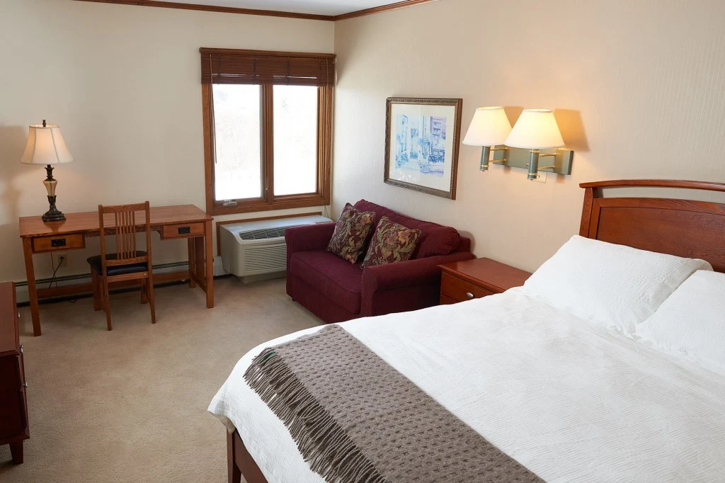 Private residential bedroom with bed, desk, and seating area