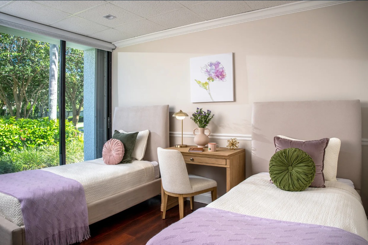 Shared bedroom with two beds, desk, and garden view window