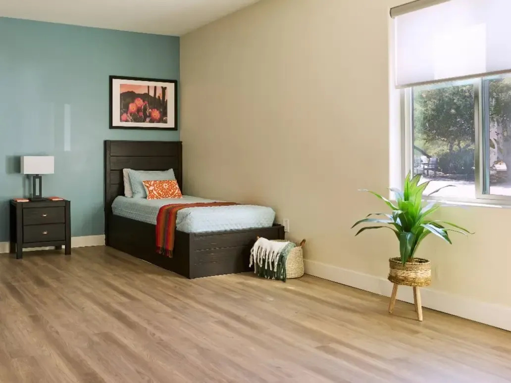 Bright private bedroom with single bed, nightstand, and window view.