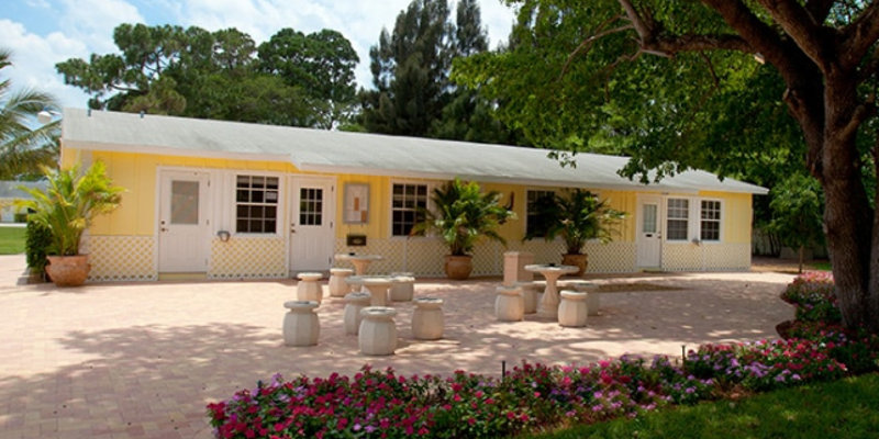 Yellow building with outdoor seating and lush greenery.