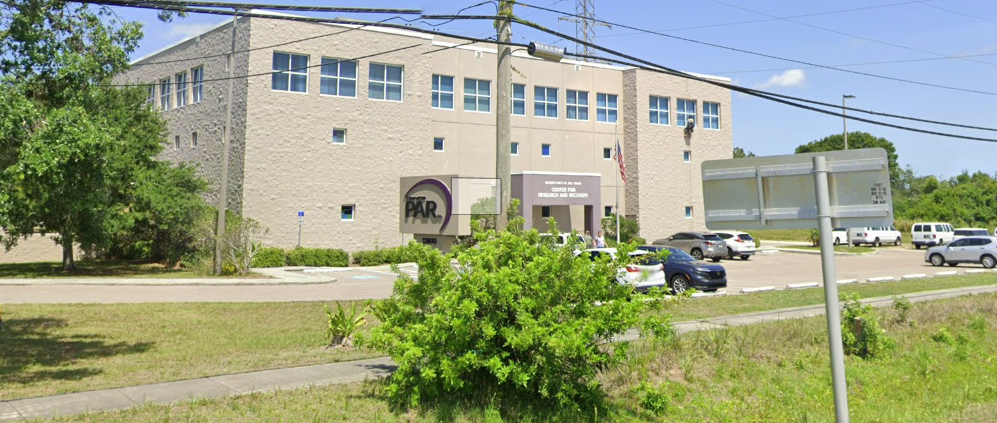 Three-story rehab facility with parking lot and trees
