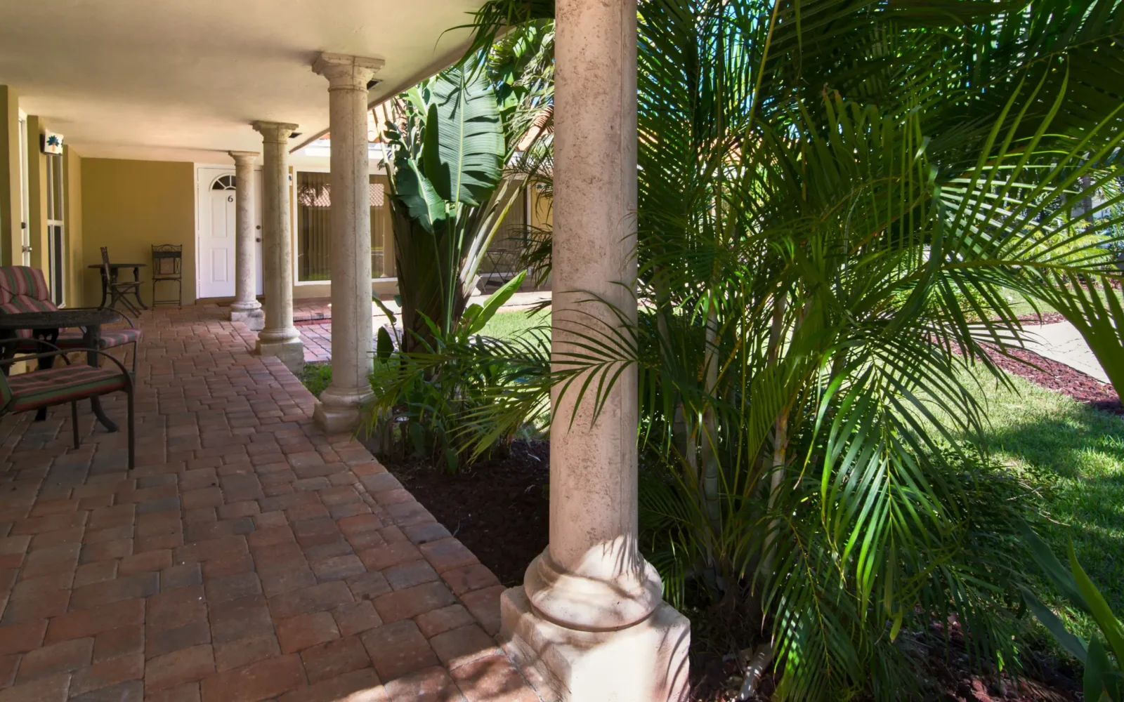 Shaded rehab facility porch with columns and tropical plants