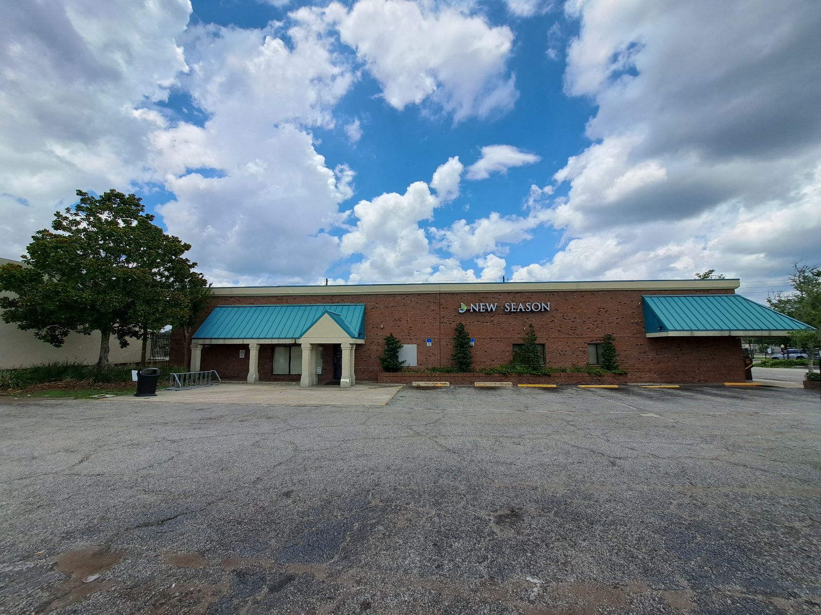 Brick exterior of New Season clinic with teal roof and parking lot