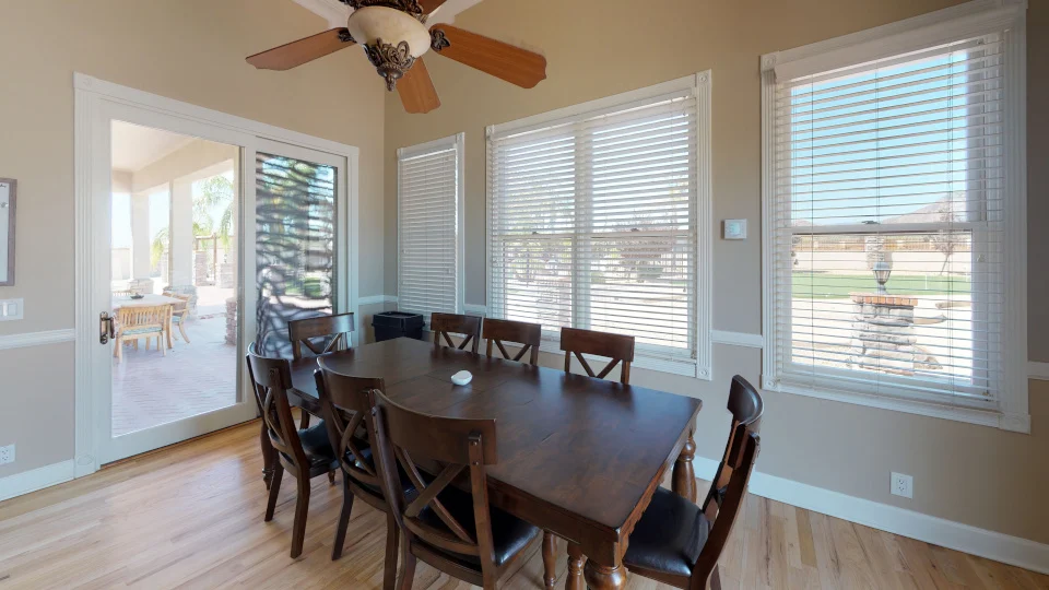 Dining room with wooden table, chairs, and large windows
