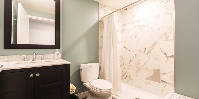  A clean, modern bathroom with a spacious walk-in shower, elegant marble tiles, and a sleek vanity offers a comfortable and refreshing space.