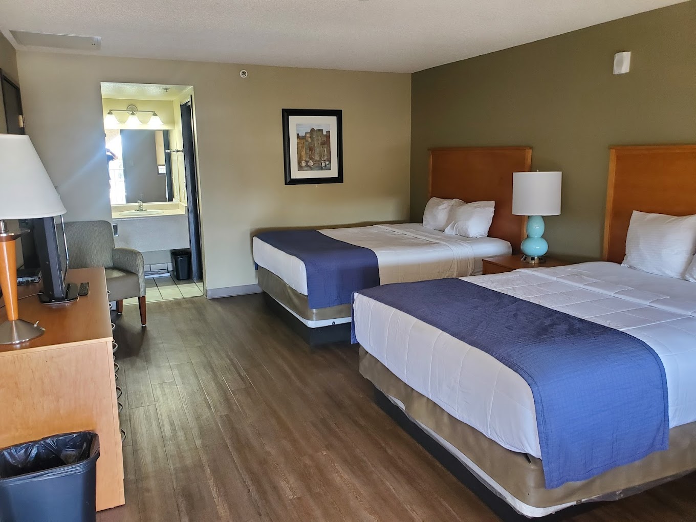 Room with two double beds, wooden furniture, and a framed picture