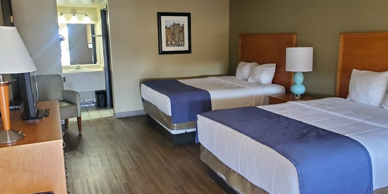  A comfortable rehab center room featuring two neatly made beds, warm lighting, modern decor, and a clean, inviting atmosphere for rest.