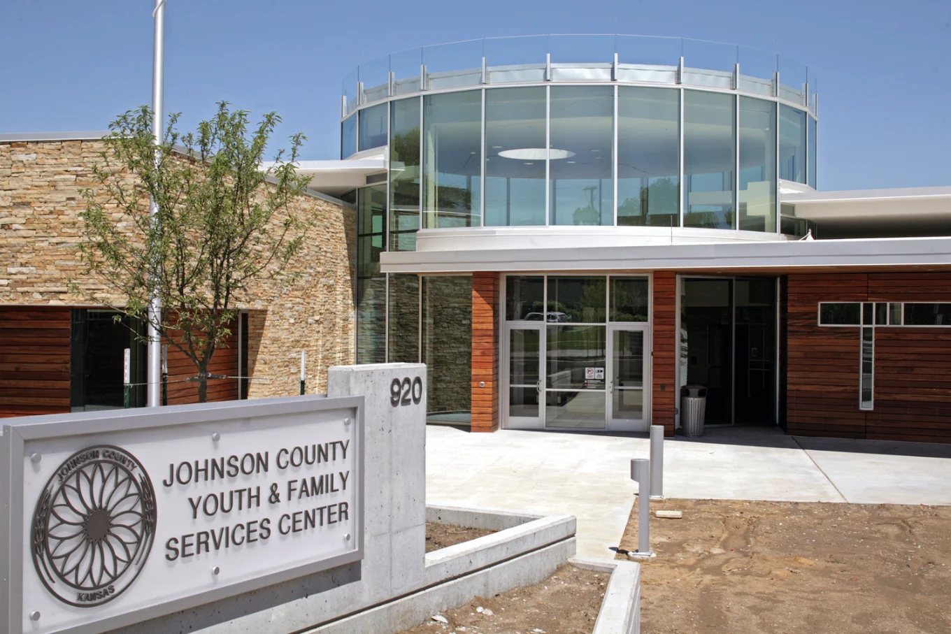 Modern facility entrance with glass, wood, and stone exterior