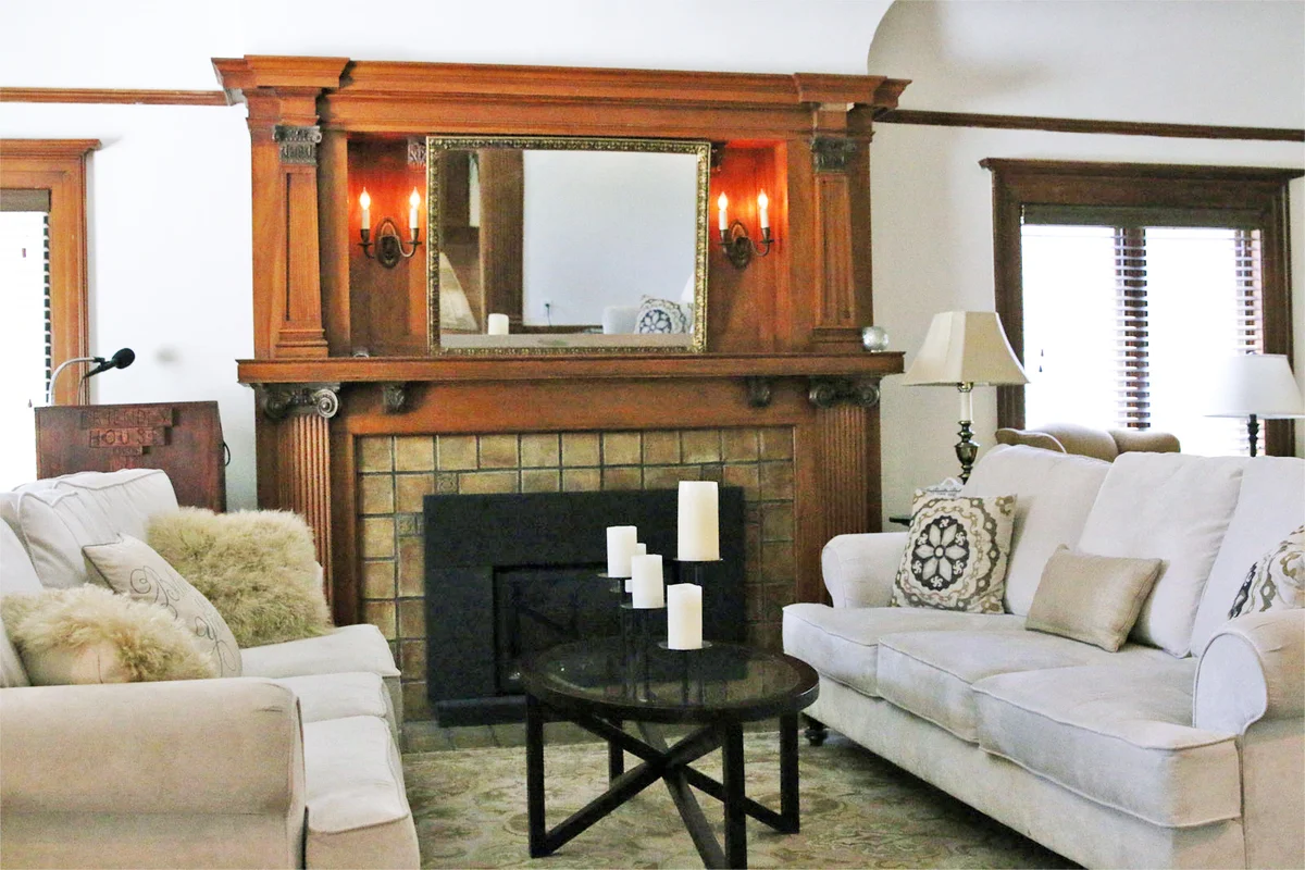 Cozy lounge with sofas, pillows, and classic wooden fireplace