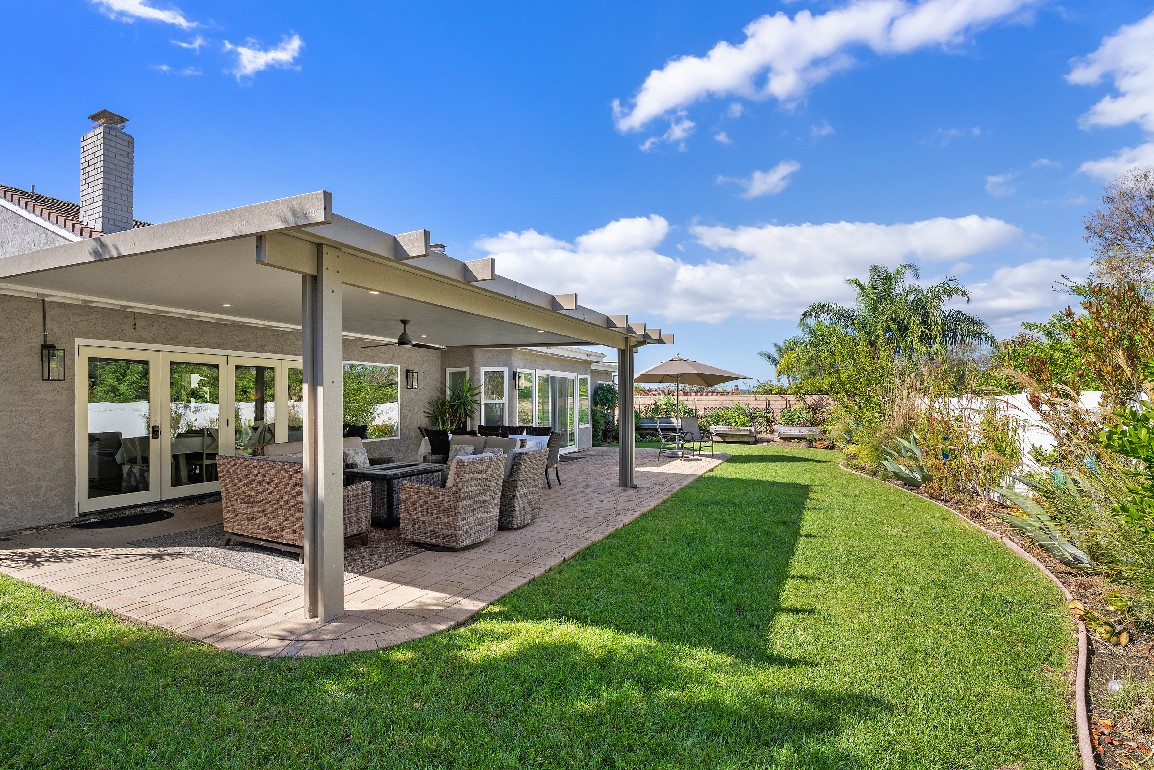 Landscaped backyard with green lawn and covered patio seating