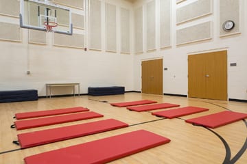Gymnasium with red exercise mats and a basketball hoop for group fitness activities in Maumee treatment center