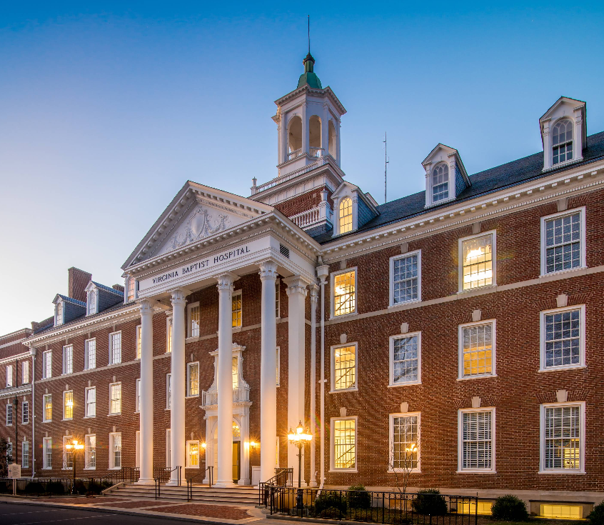 Historic brick hospital with columns and cupola at dusk
