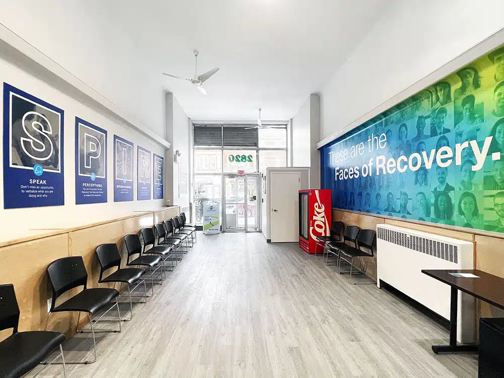 Long waiting room with chairs and Faces of Recovery mural
