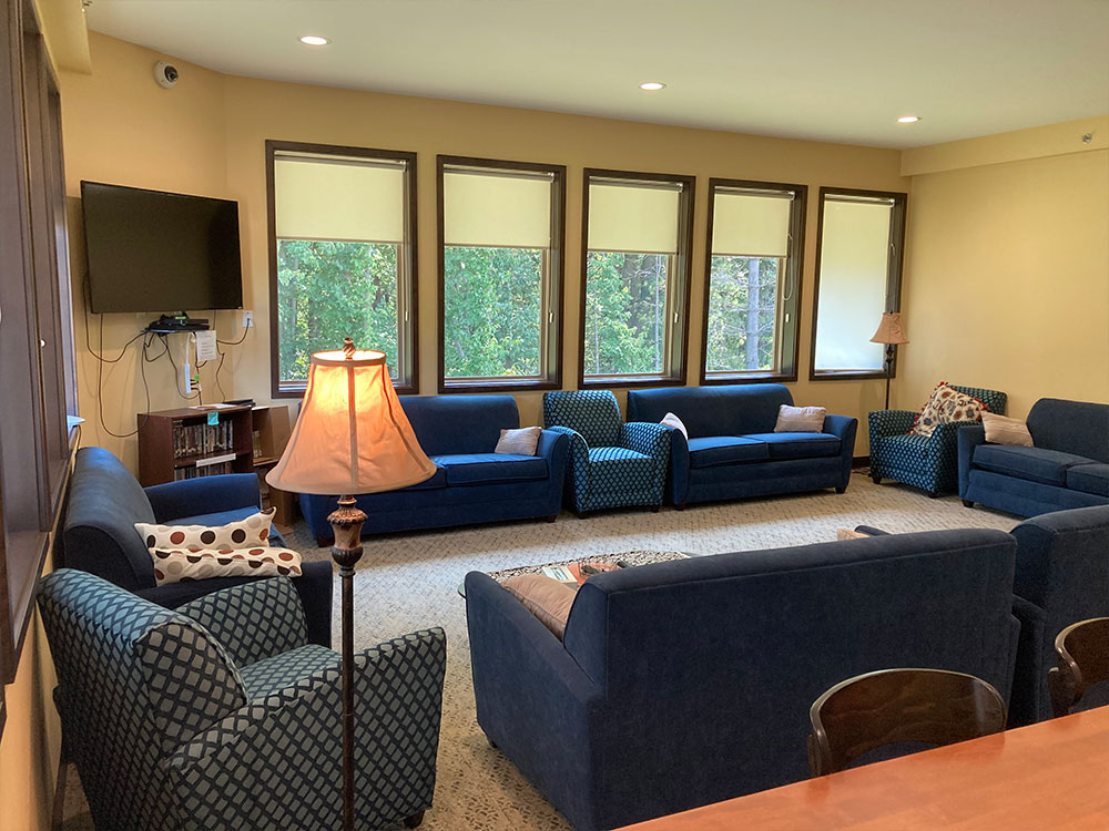 Cozy lounge with blue sofas, TV, and large windows