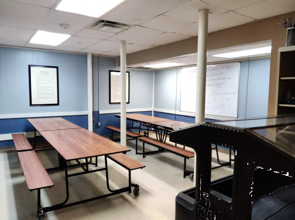 Dining area with long tables and benches beside whiteboard