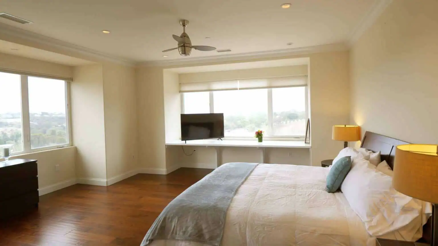 Bright bedroom with bed, ceiling fan, and large windows