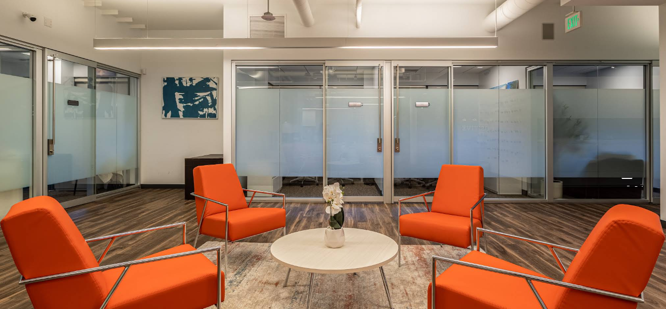 Modern therapy room with orange chairs arranged around a round table.