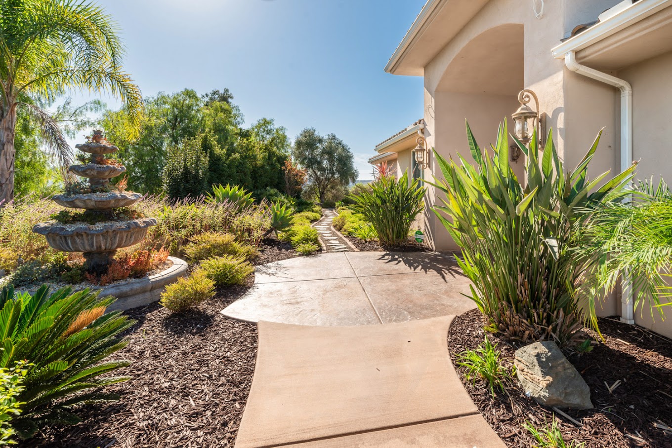 Outdoor walkway in front of facility with landscaping and a fountain.