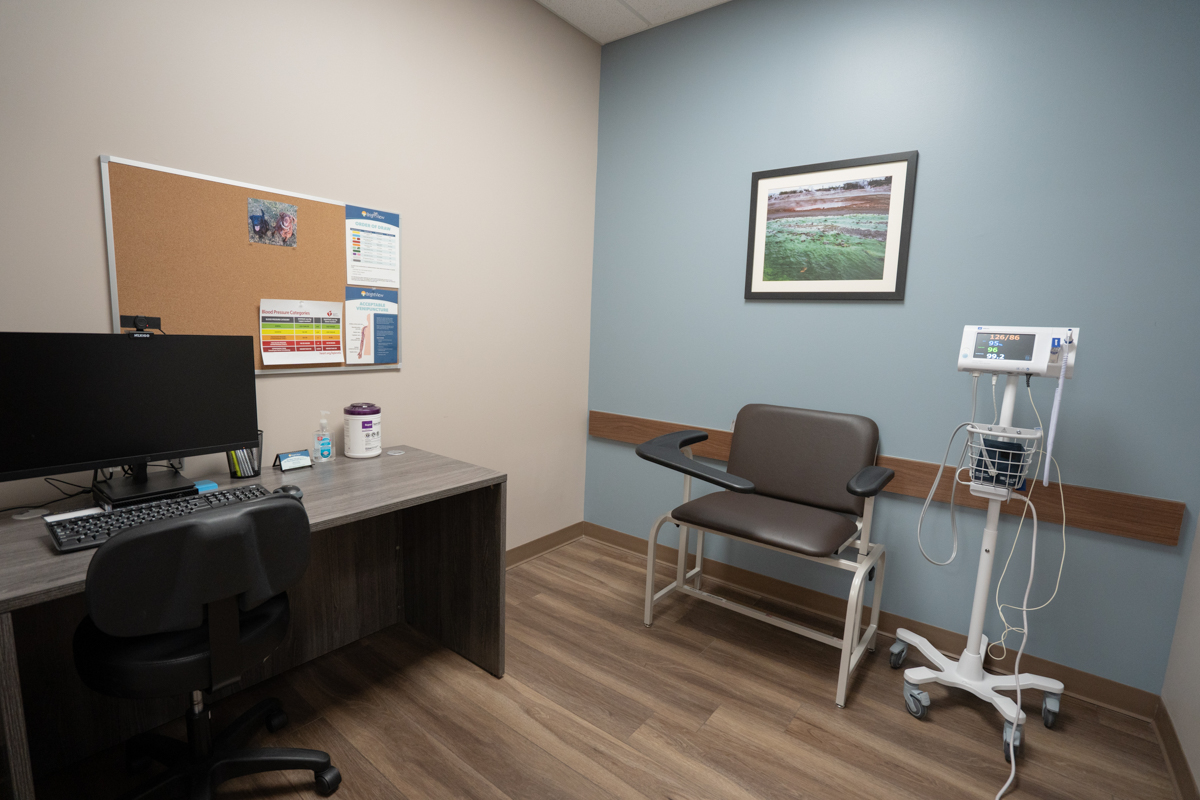 Exam room with patient chair, desk, and vital signs monitor