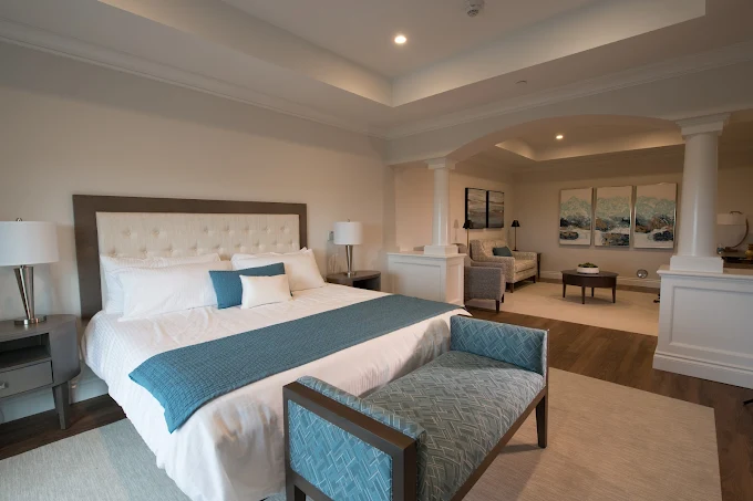 King bed with blue accents and seating area under tray ceiling