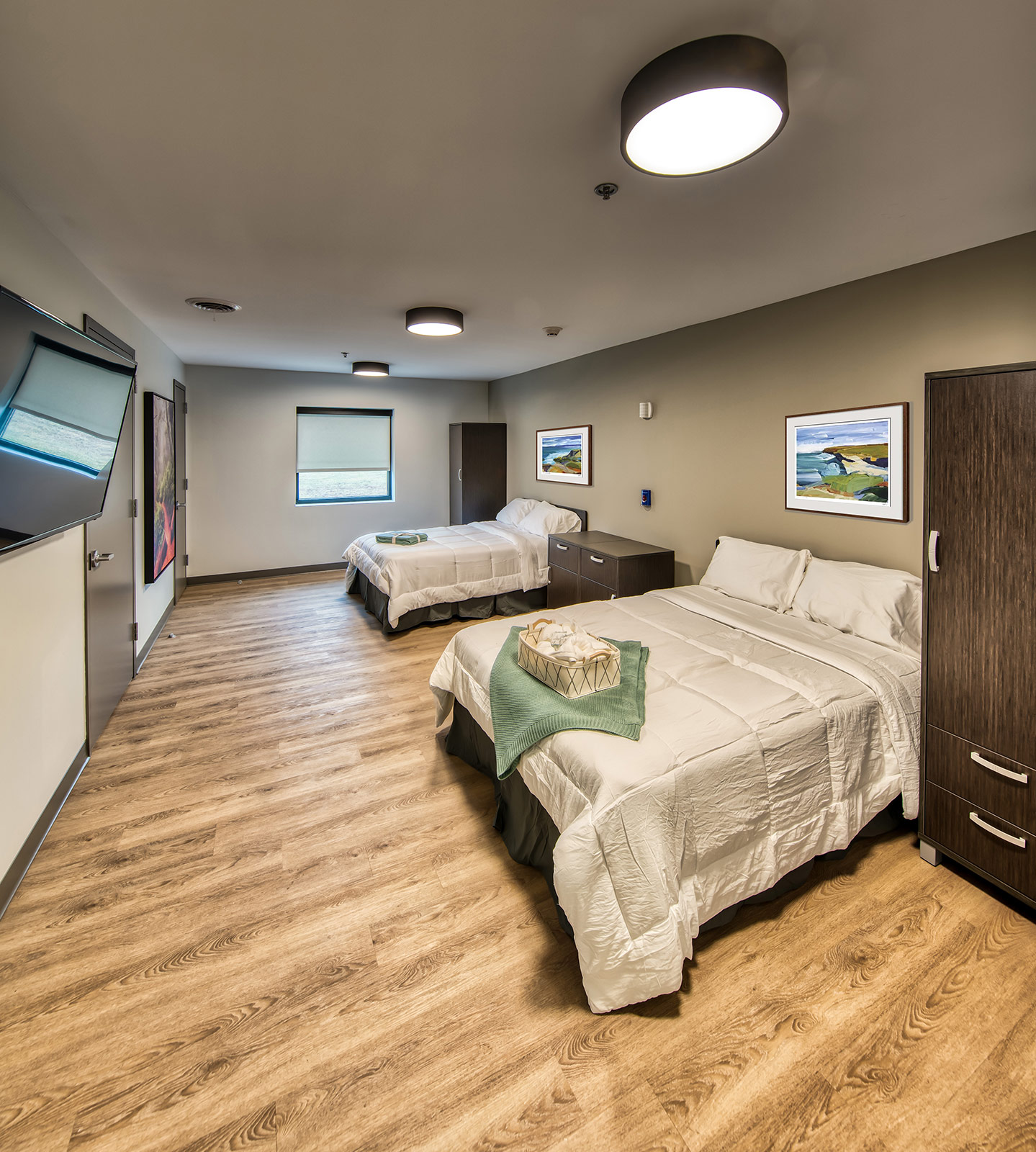 Two-bed room with wood floors and wall art