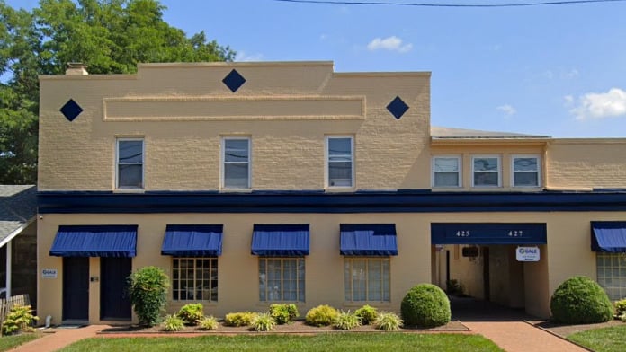 Yellow brick building with blue awnings and arched walkway
