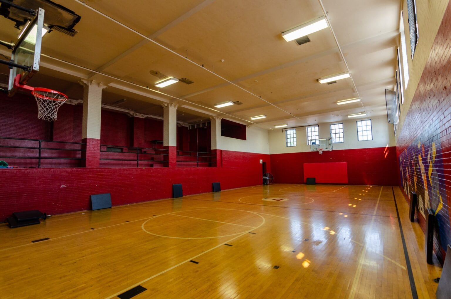 Indoor basketball court with red brick walls and wood flooring