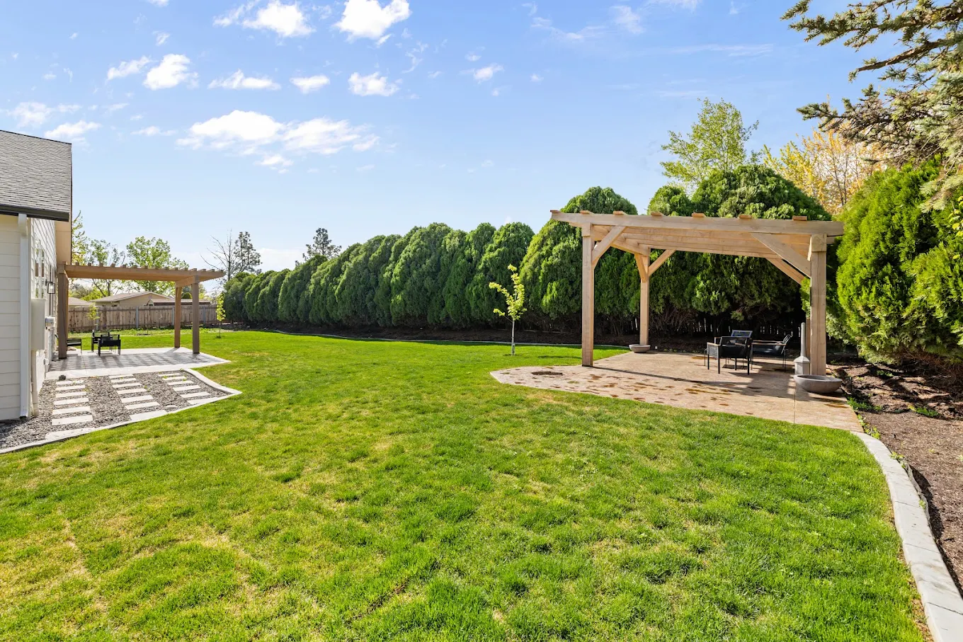 Spacious grassy backyard with two covered seating areas