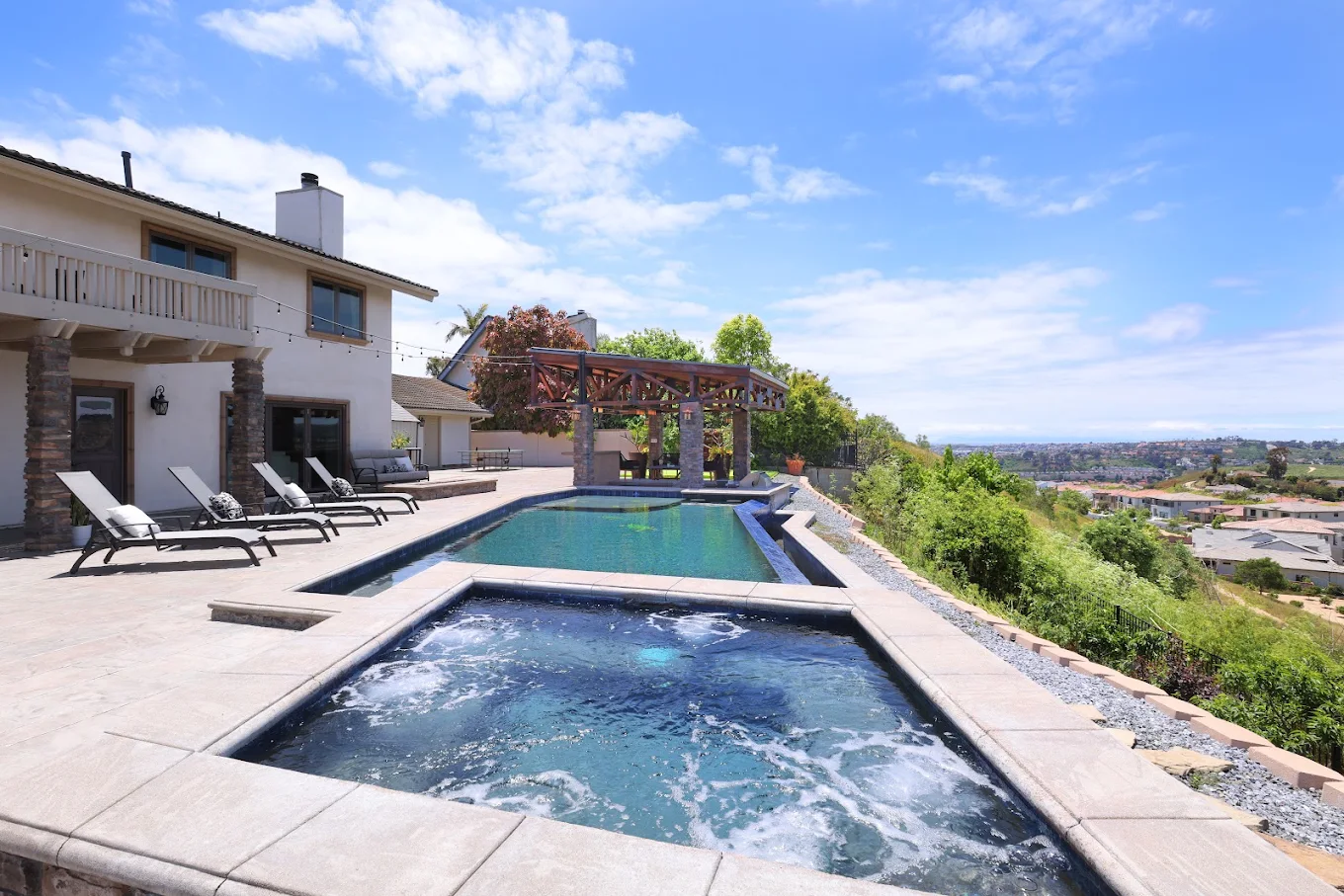 Outdoor pool and spa with lounge chairs and hillside views