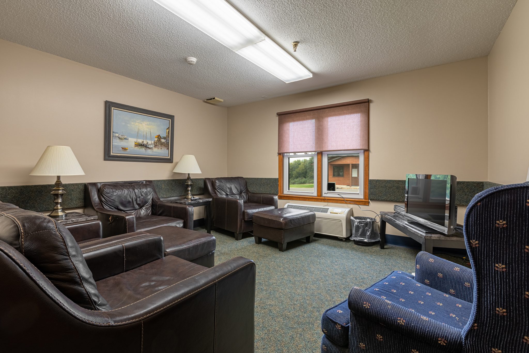 Resident lounge featuring leather armchairs, a blue patterned chair, and TV setup.